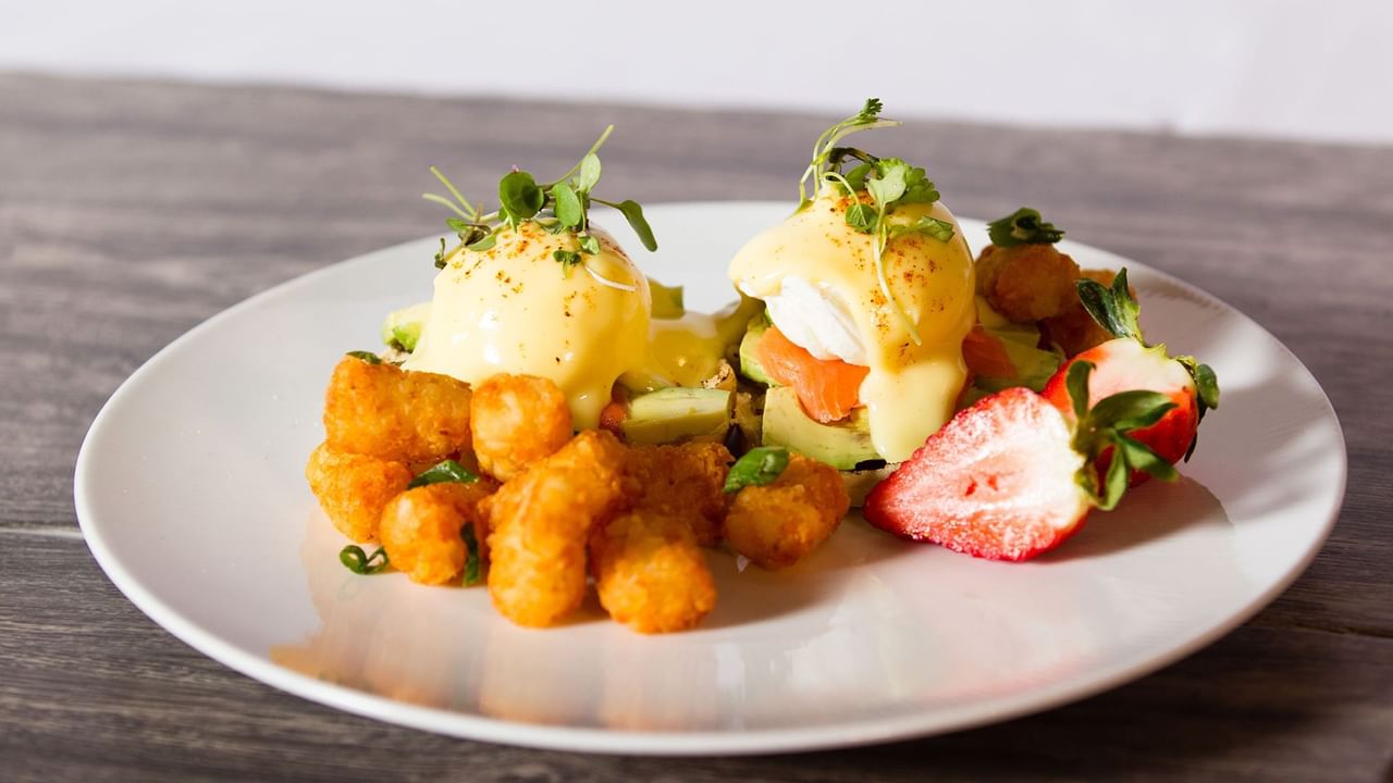 Smoked salmon eggs benedict with fruits and potatoes