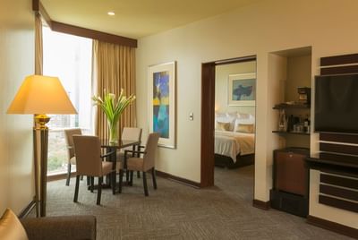 Senior Suite living area with a dining table, TV, and  a doorway leading to the cozy bedroom at Hotel Los Delfines & Casino