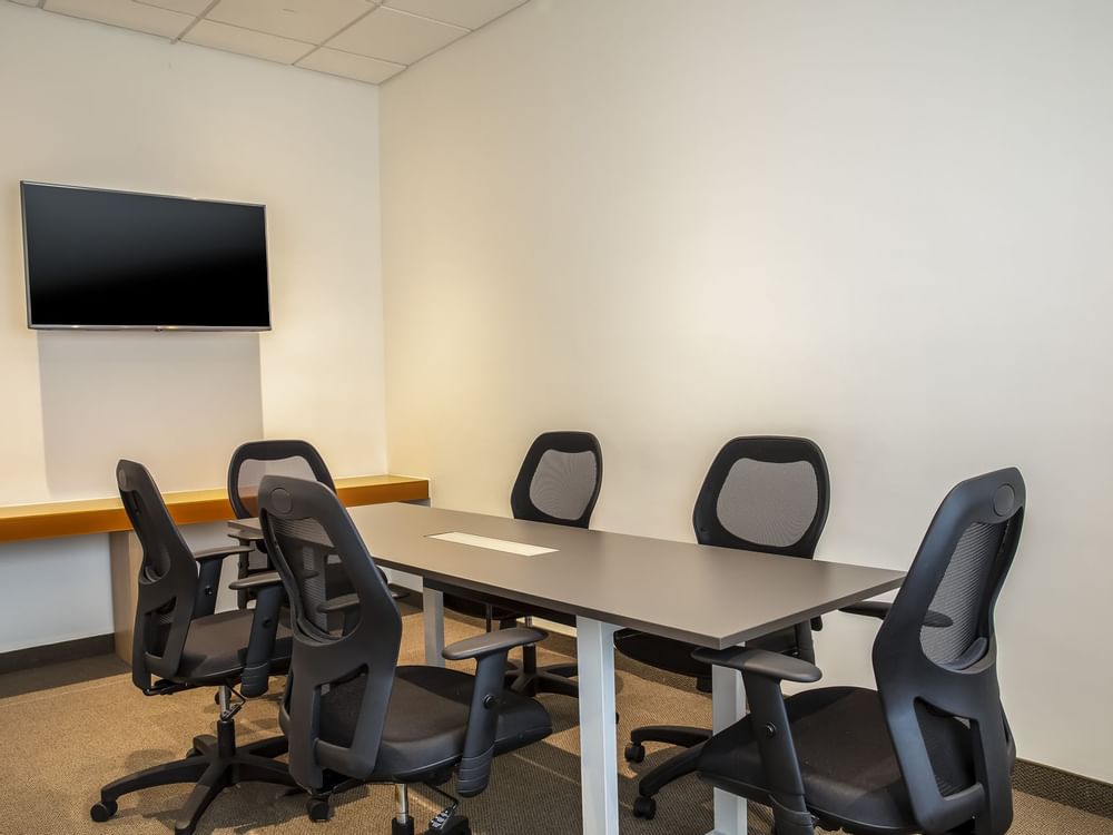 Pequeña mesa de reuniones y televisor de pared en una sala de reuniones de One Hotels