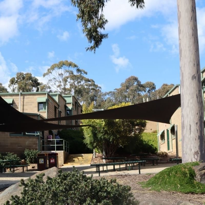 La Trobe University buildings with shaded seating area and surrounding greenery.
