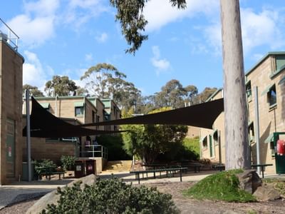 La Trobe University buildings with shaded seating area and surrounding greenery.