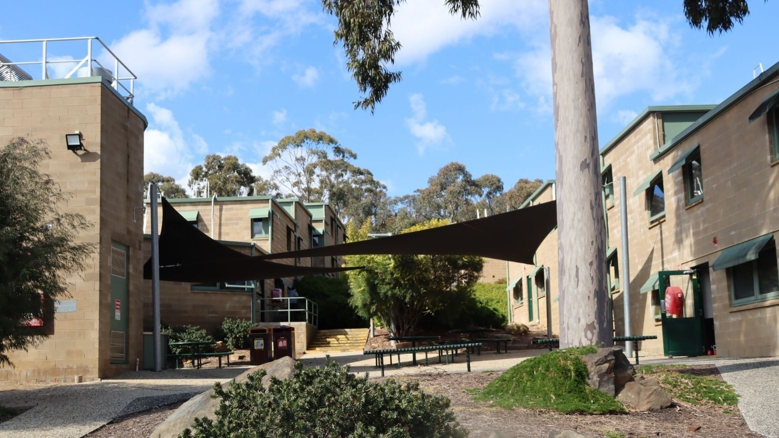 La Trobe University buildings with shaded seating area and surrounding greenery.