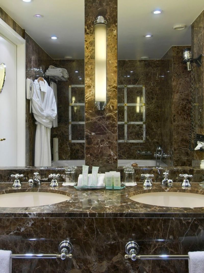 Royal Suite bathroom featuring sink with roses in vases by wall mirrors at Warwick Grand Place Brussels