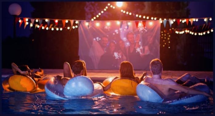 People sitting in a pool & watching a movie on a projector screen at The Diplomat Resort