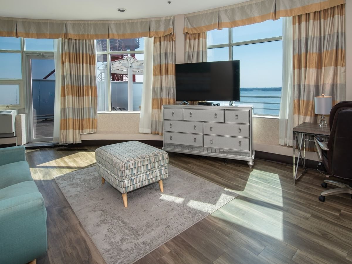 Coast Waterfront Suite with a couch, ottoman, TV, dresser, and office chair by a window at Coast Lonsdale Quay Hotel