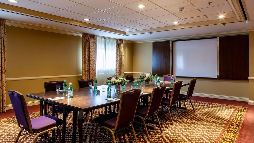 Purple chairs by a wood table under a grid ceiling near a white screen in Evans at Warwick Denver