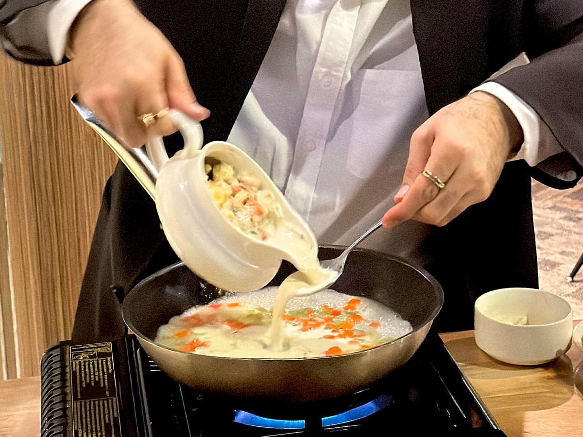 Chef pouring soup into pan on stove at Minnoz Restaurant + Lounge in Nanaimo at Coast Bastion Hotel.