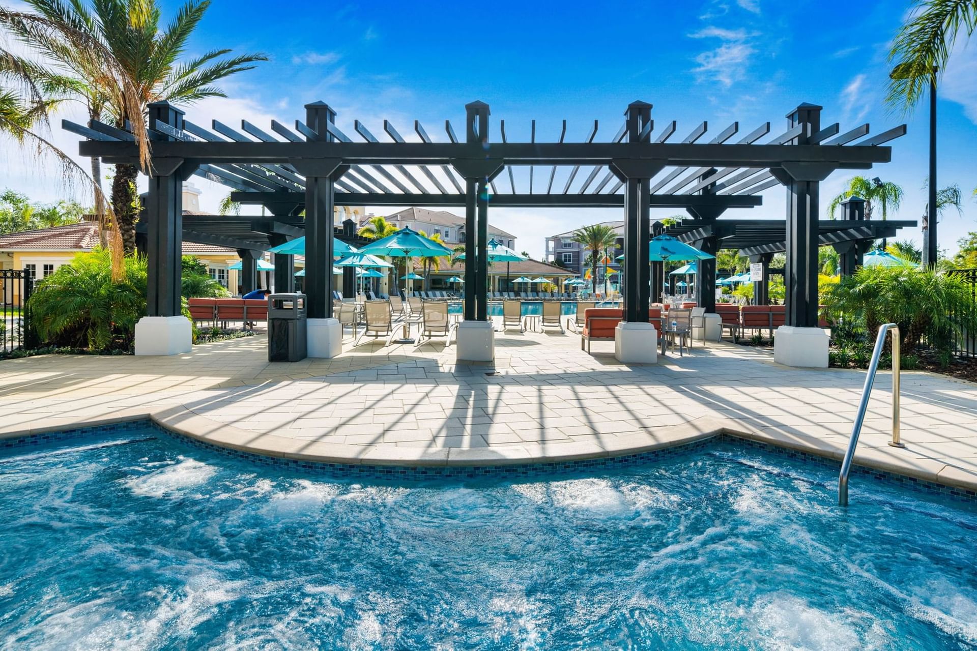 Outdoor hot pool and patio with covered area and lounge chairs at Vista Cay Resort By Millenium