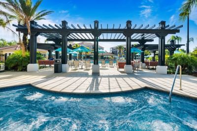Outdoor hot pool and patio with covered area and lounge chairs at Vista Cay Resort By Millenium