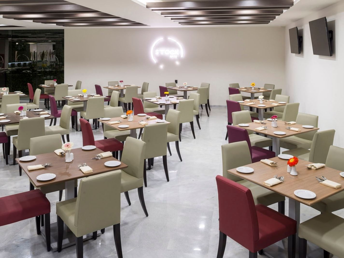 Stock Café dining room with neatly set tables, soft lighting, and a spacious layout at Real Inn Celaya