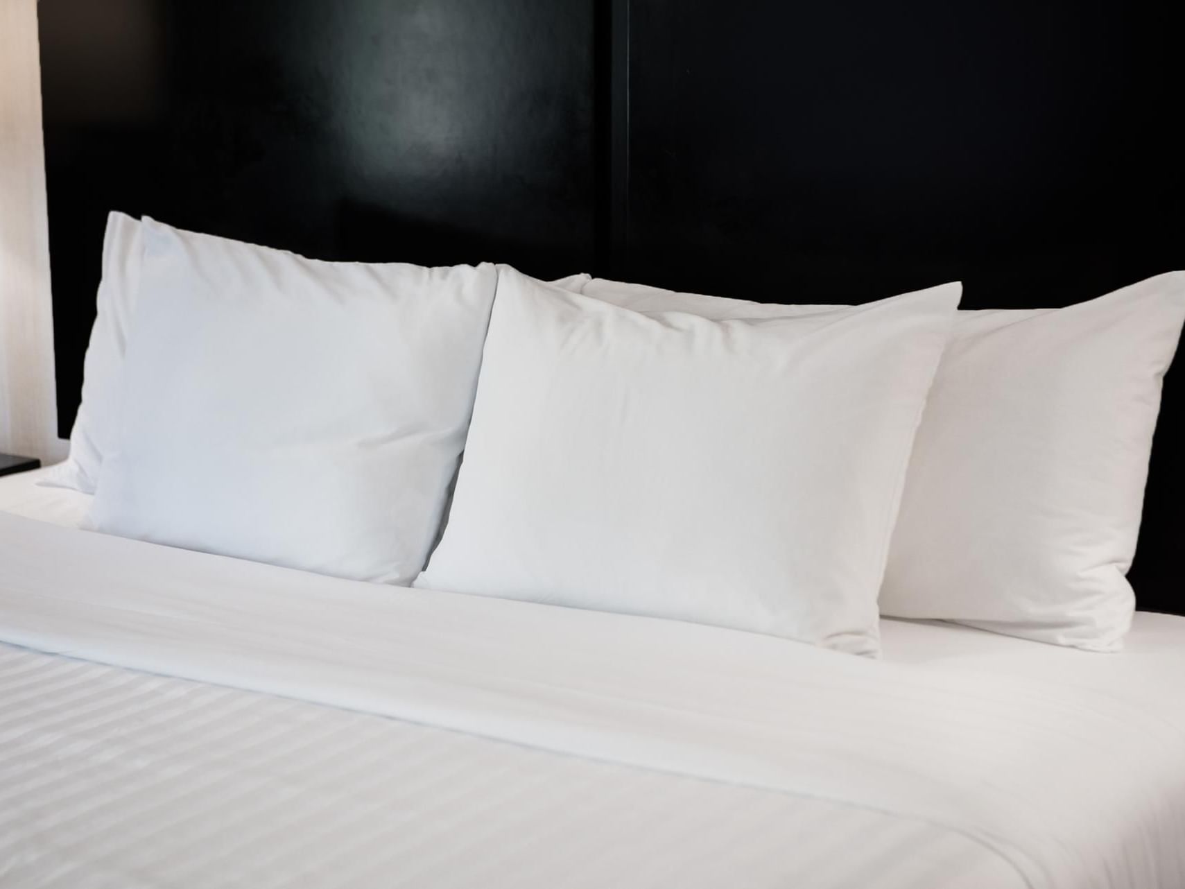 White bed with three pillows on black headboard at Garden Executive Hotel in South Plainfield.