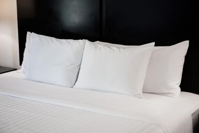 Close-up of crisp white pillows & linens on a bed in Standard One Full Accessible Non-Smoking Room at Garden Executive Hotel