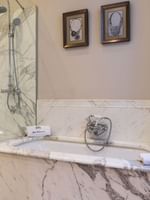 Deluxe Suite Parisienne bathroom featuring a bathtub and a glass shower at Hotel Westminster Paris