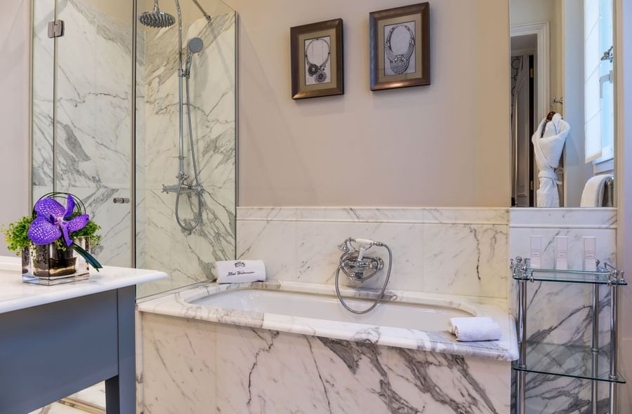 Deluxe Suite Parisienne bathroom featuring a bathtub and a glass shower at Hotel Westminster Paris