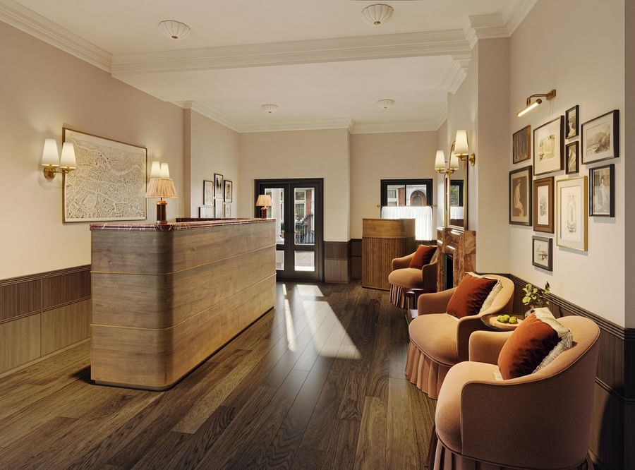 Reception desk placed by chairs and framed art on a wall at The Capital Hotel, Apartments and Townhouse