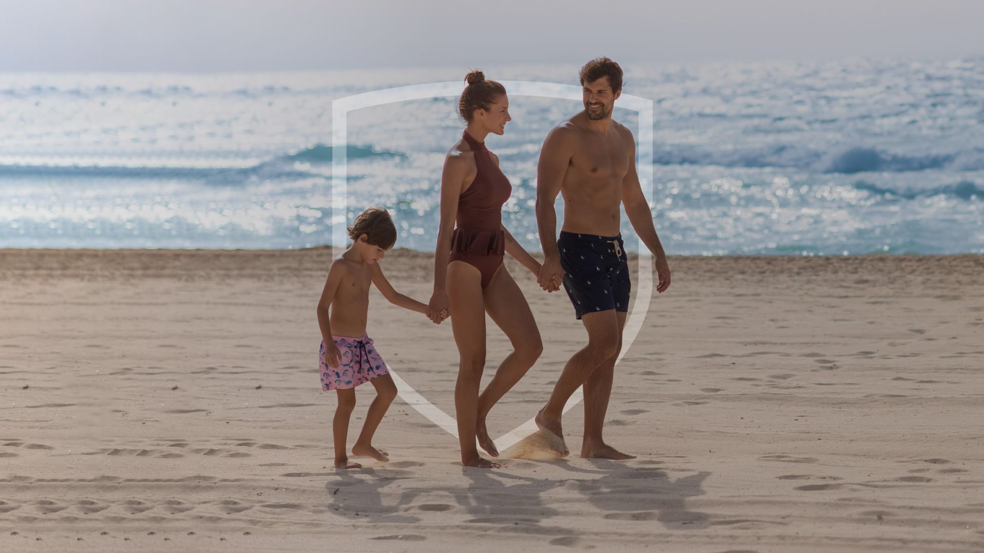 Una familia tomados de la mano y caminando por la playa en FA Hotels