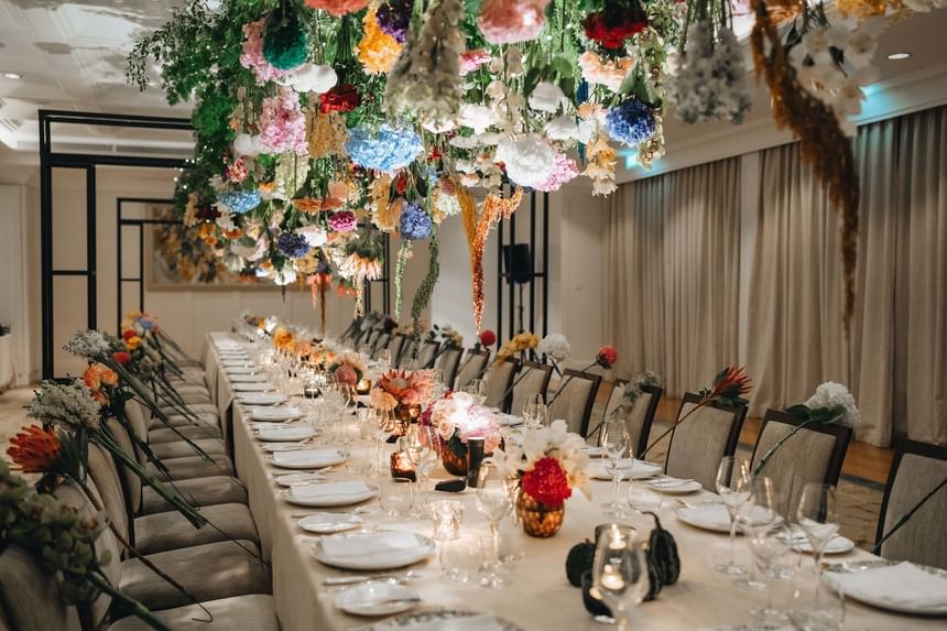 Colorful flower canopy over a dining table set with fine plates and glassware at Park Hyatt Saigon