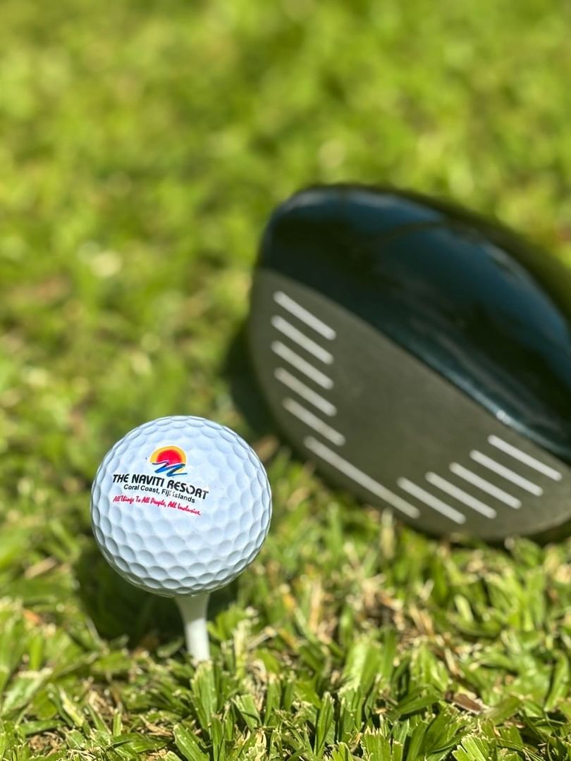 White golf ball on a tee by a driver club under the bright at The Naviti Resort in Korolevu.