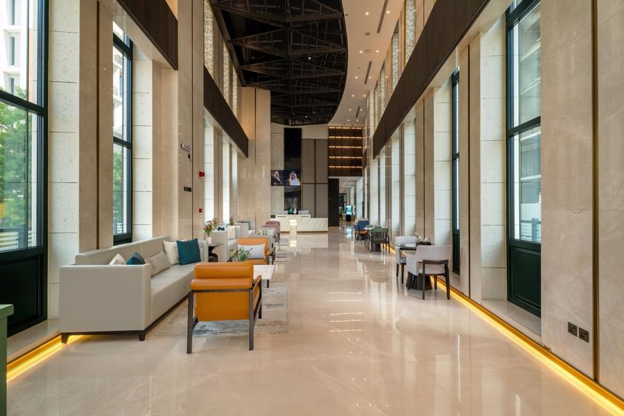 Spacious hotel lobby with high ceiling and leather armchairs near bright windows beside desk at Naviti by Warwick Jeddah