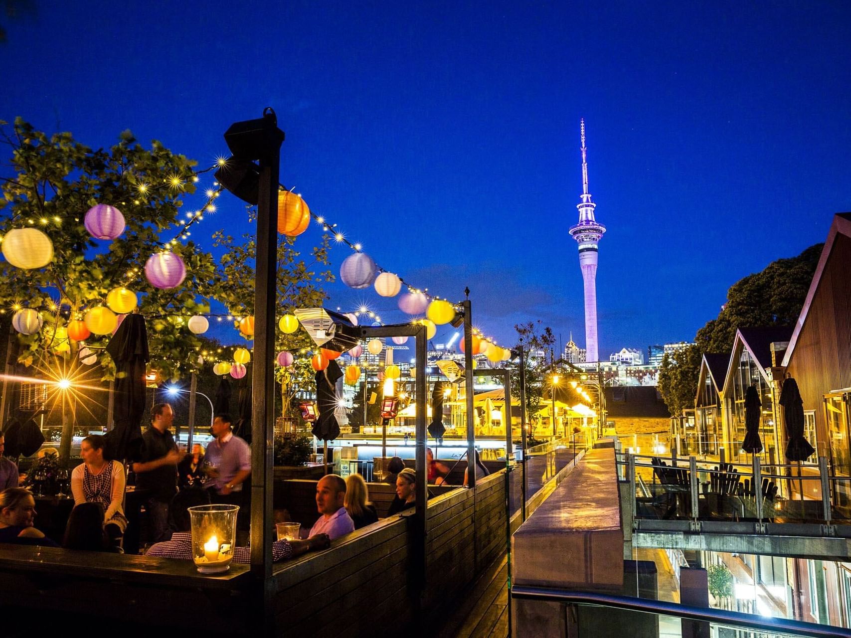 Illuminated outdoor dining area with Auckland tower view at Hotel Grand Chancellor
