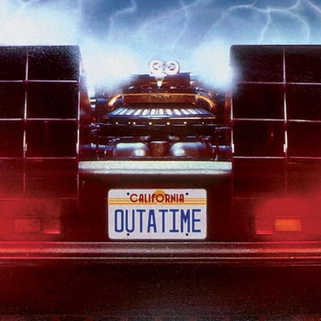 DeLorean time machine lit by stage lights in front of a full orchestra performing Back to the Future in Concert