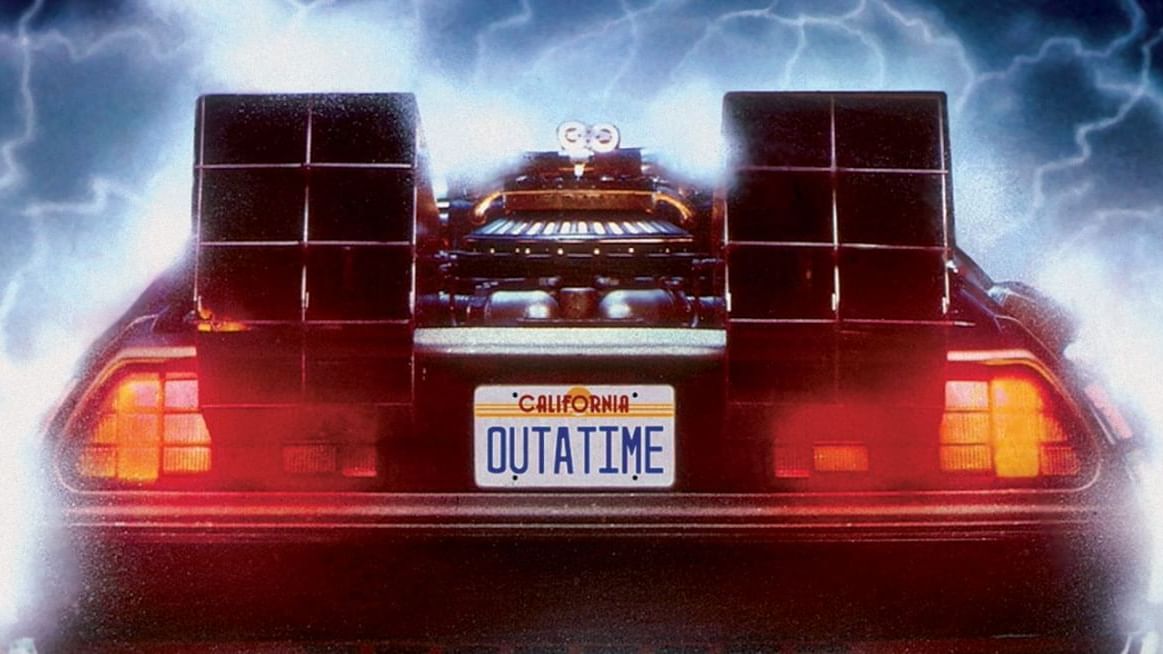 DeLorean time machine lit by stage lights in front of a full orchestra performing Back to the Future in Concert