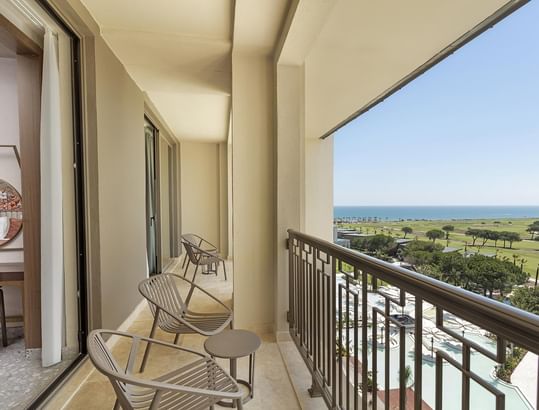 Family Room Sea View's balcony with chairs, table, and view of sea and resort.