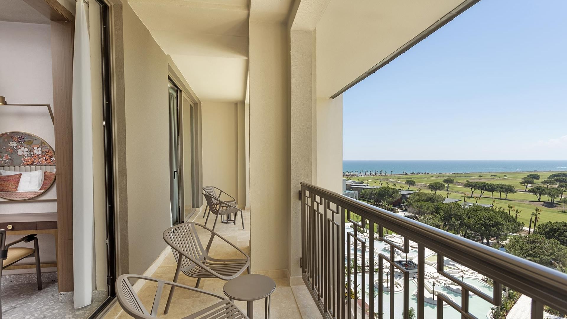 Family Room Sea View's balcony with chairs, table, and view of sea and resort.