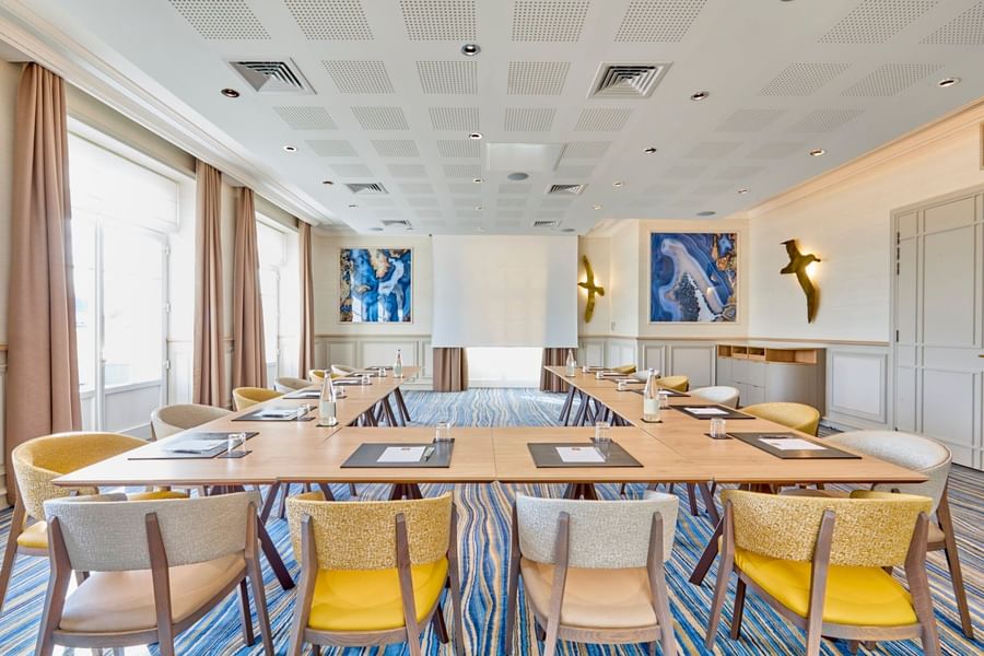 U-shaped table set up in a meeting room with colourful wall art at Le Grand Hôtel des Thermes