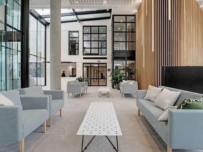 Modern lobby with light blue sofas, wooden slat wall, and floor-to-ceiling windows at UniLodge Auckland Central