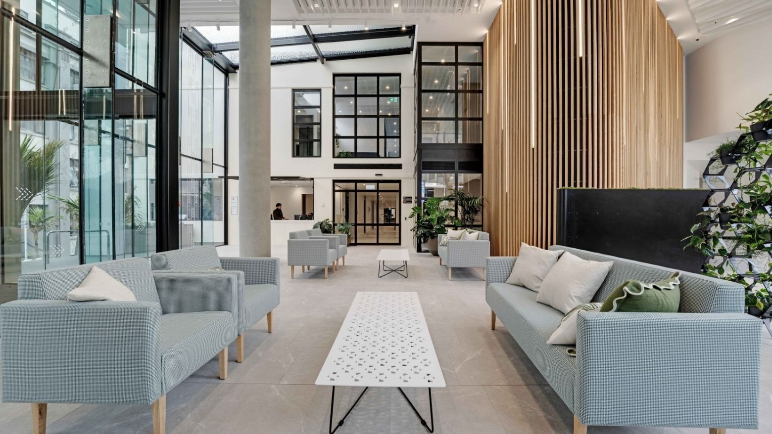 Modern lobby with light blue sofas, wooden slat wall, and floor-to-ceiling windows at UniLodge Auckland Central