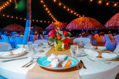Beautifully set dining table with vibrant floral centerpieces under string lights at Amsterdam Manor Beach Resort