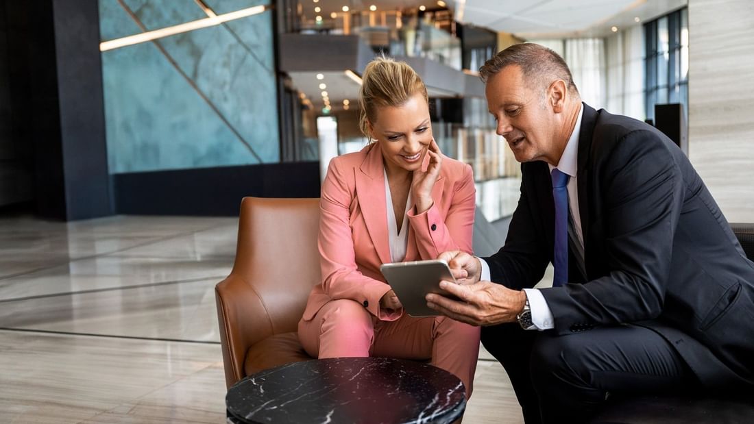 Two guests sitting in hotel lobby looking at iPad