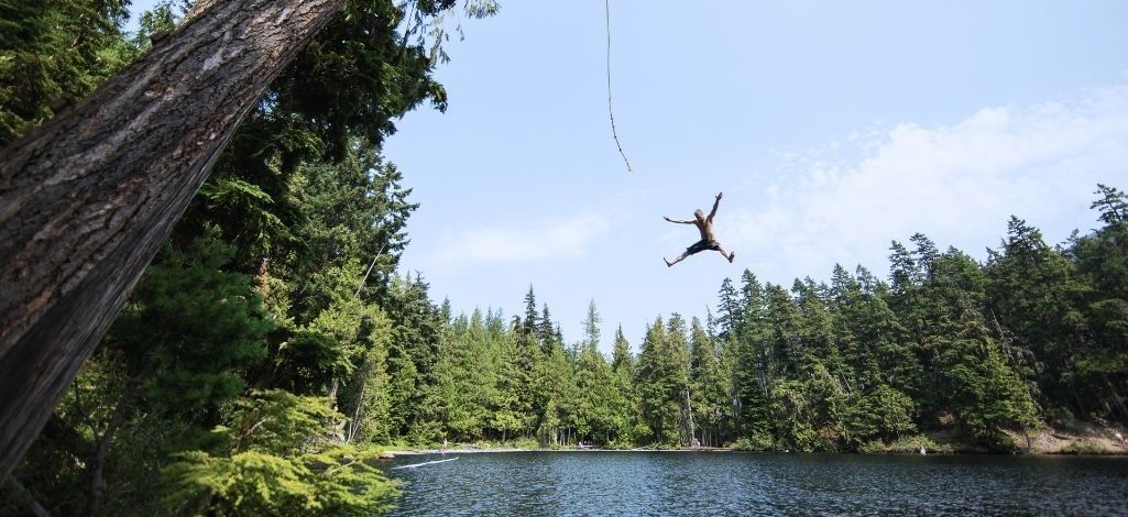 Whistler outdoor adventure with a person jumping into a forest lake