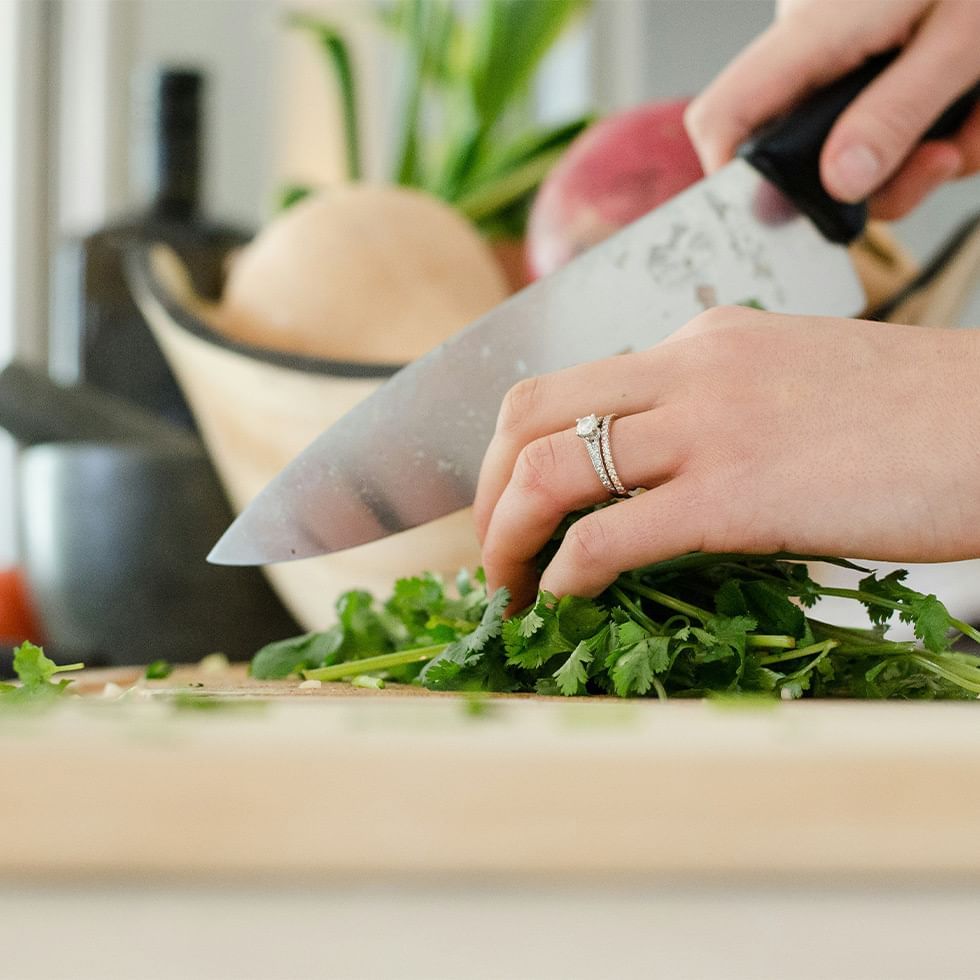 Close-up of hands chopping fresh cilantro in Cooking Class at Falkensteiner Hotel Belgrade