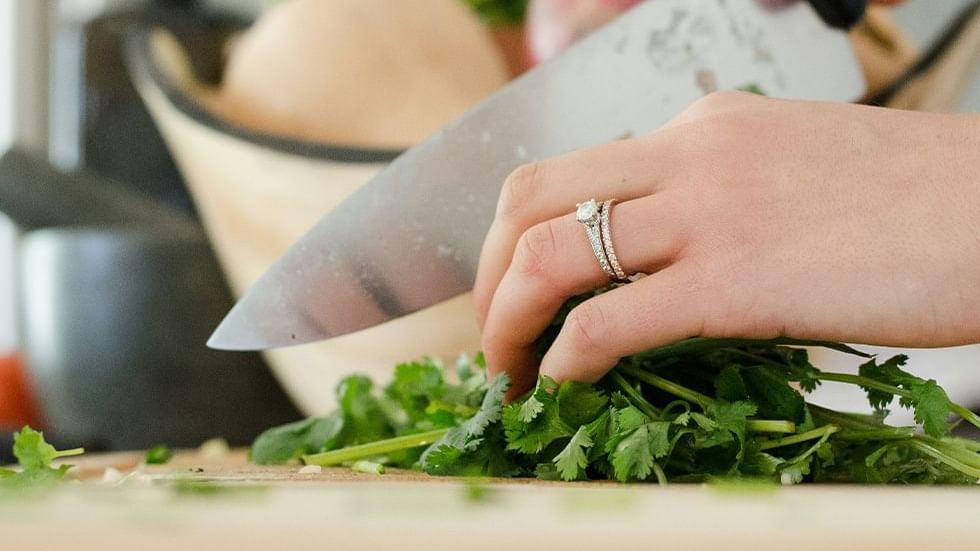 Close-up of hands chopping fresh cilantro in Cooking Class at Falkensteiner Hotel Belgrade