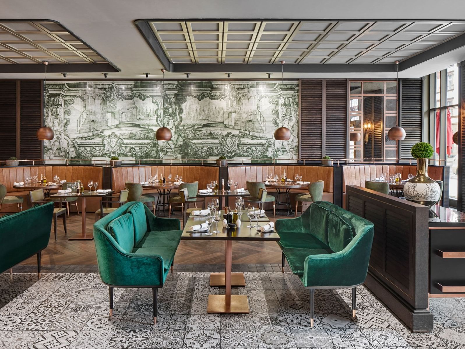 Elegantes Restaurant mit grünen Samtsitzen, Holztischen und kunstvollem Wandbild – Titanic Chaussee Berlin.