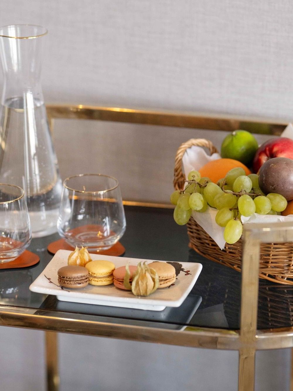 Fruit en macarons op een gouden tafel bij de 24-uursroomservice in Hotel Barsey by Warwick in Brussel.