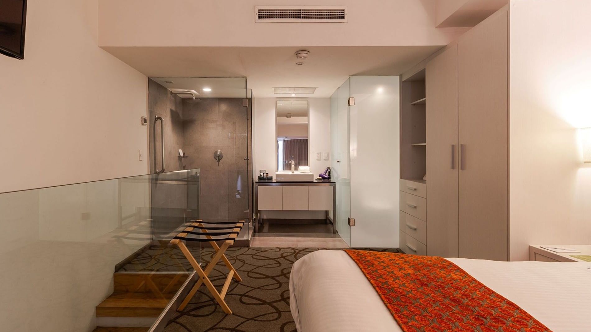 Queen Loft Bed open-plan bathroom featuring a glass shower and a white vanity at Camino Real Puebla Angelopolis