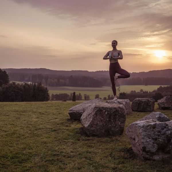 Lady doing yoga on a rock during sunrise, Falkensteiner Hotels