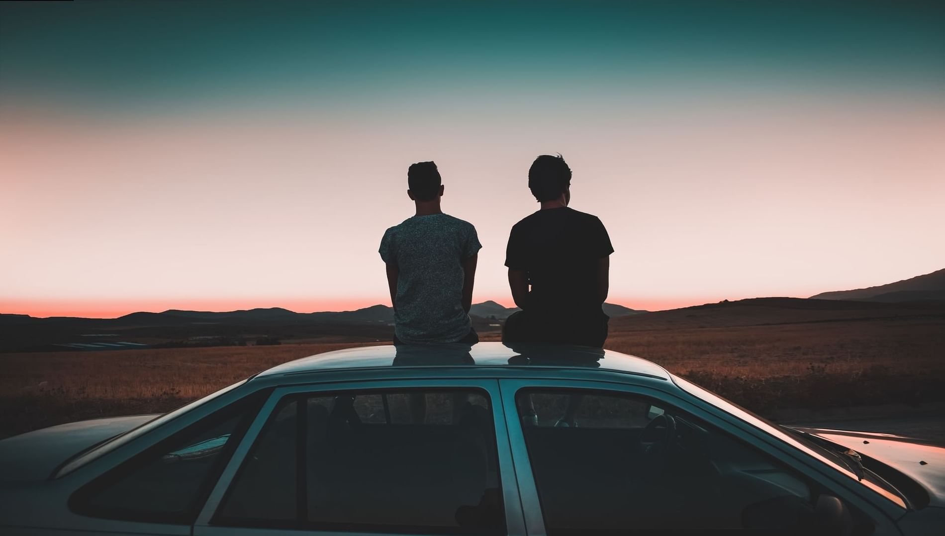 Two people sitting on a car roof near The Originals Hotels