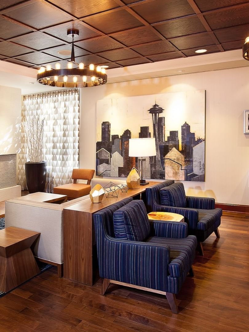 Modern lobby featuring blue armchairs by a fireplace under ring chandeliers at Warwick Seattle