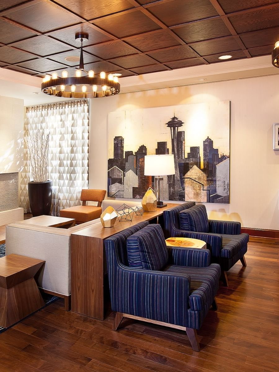 Modern lobby featuring blue armchairs by a fireplace under ring chandeliers at Warwick Seattle