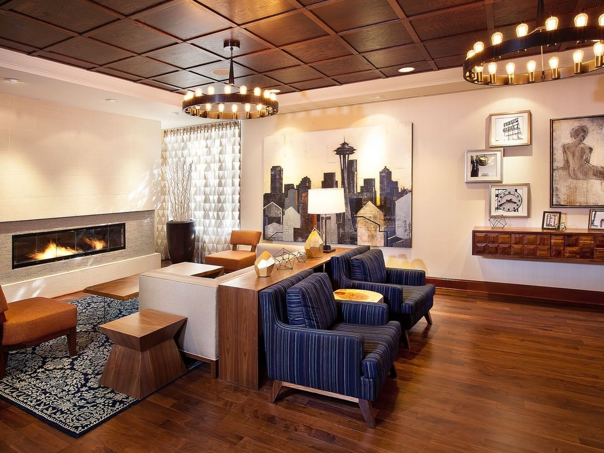 Modern lobby featuring blue armchairs by a fireplace under ring chandeliers at Warwick Seattle
