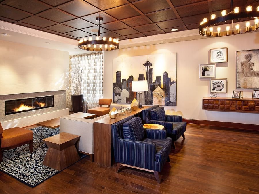 Modern lobby featuring blue armchairs by a fireplace under ring chandeliers at Warwick Seattle