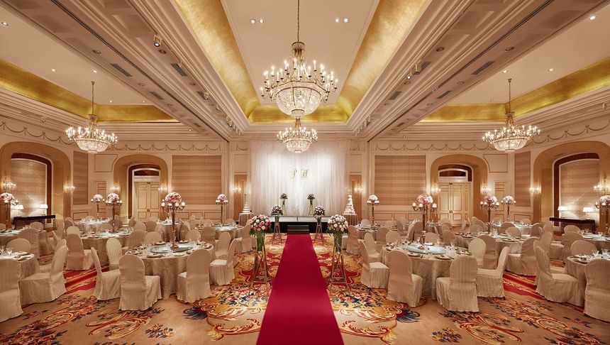 Red carpet aisle leads through a chandelier-lit ballroom with floral centerpieces at Park Hyatt Saigon