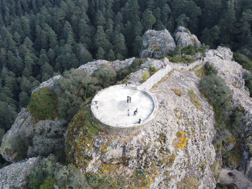 Mirador de piedra sobre acantilado rodeado de bosque denso cerca de Camino Real Hotels