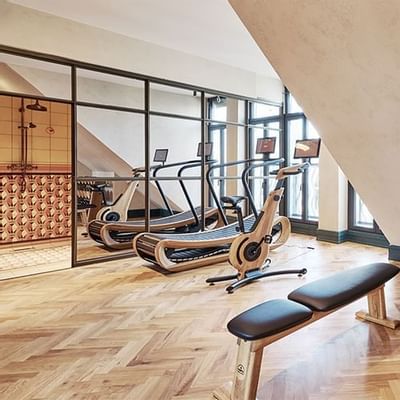 Fitness room with wooden flooring, equipped with a weight bench and exercise machines at Hotel Motto Vienna