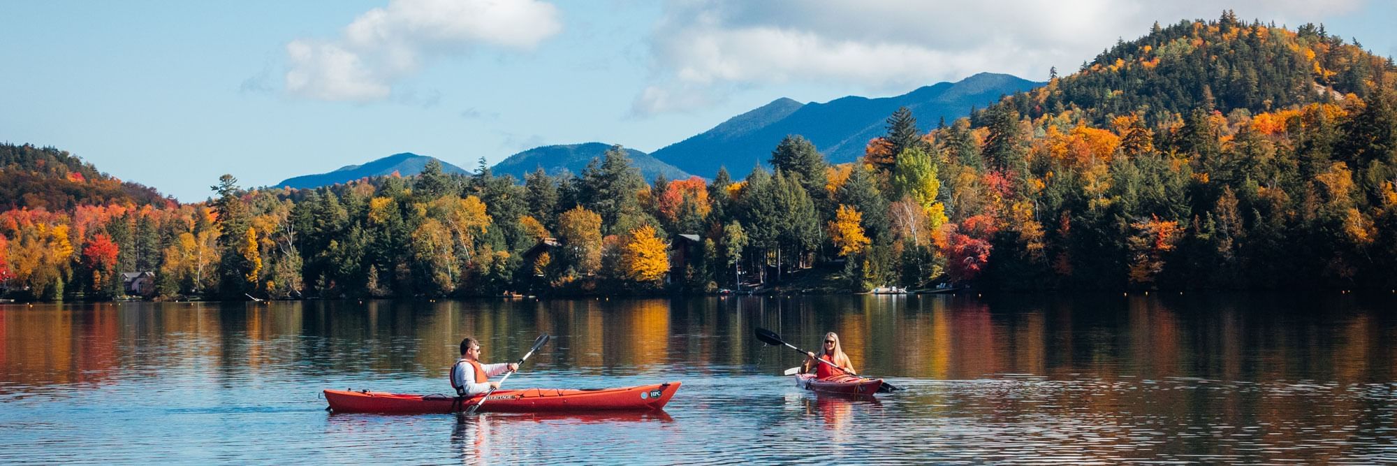 Couple kayaking on Mirror Lake surrounded by fall foliage.