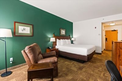 King bed, nightstands & cozy chair in Executive King at Boothill Inn & Suites